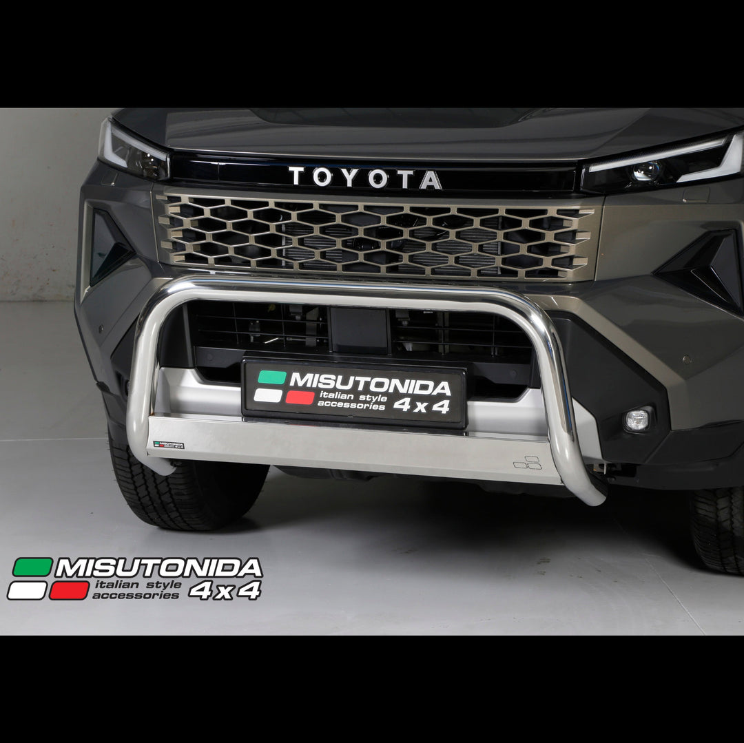 A close-up of the front of a dark gray Toyota 4x4 vehicle showing a polished silver bull bar and a Misutonida 4x4 license plate frame. The Misutonida logo is also visible as an overlay in the bottom-left corner.