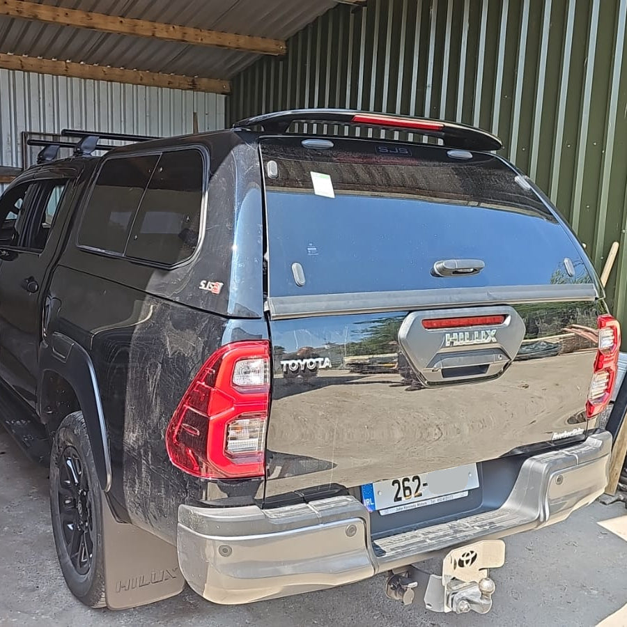 A black Toyota Hilar pickup truck with a hardtop canopy SJS pop out windows.