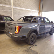 A gray Toyota double-cab pickup truck with roller shutter and roll bar parked inside a garage