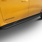 A close-up of a bright yellow Ford Wildtrak truck showing the side step protectors, door panel, and wheel area against a clean white studio background.