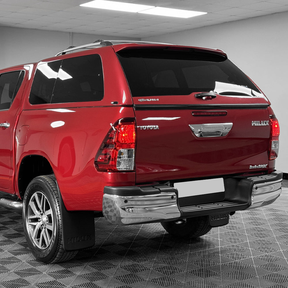 A Toyota Hilux with a Alpha GSR Hardtop Canopy attached to it, featuring dark-tinted glass windows and brushed alloy roof bars.